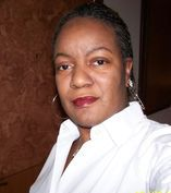 Ms. Aja Wright wearing a white blouse and looking at the camera.